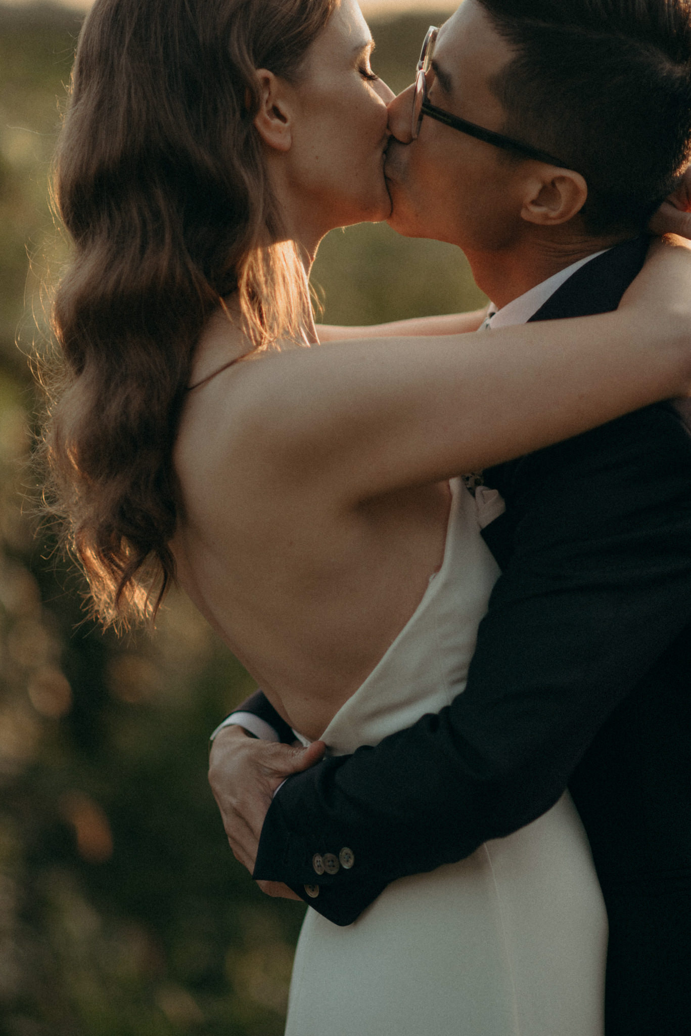 Couple kissing on wedding day in sun set