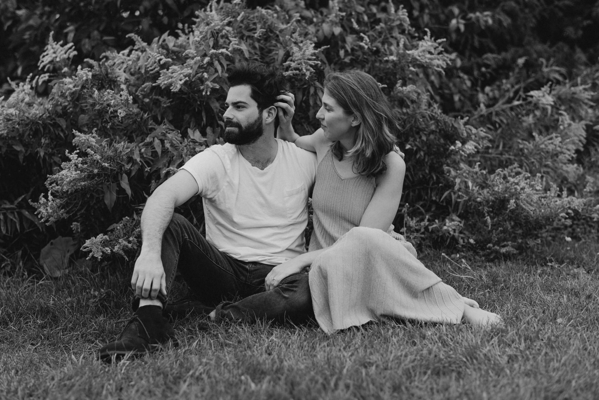 romantic black and white photo of couple sitting on grass hugging