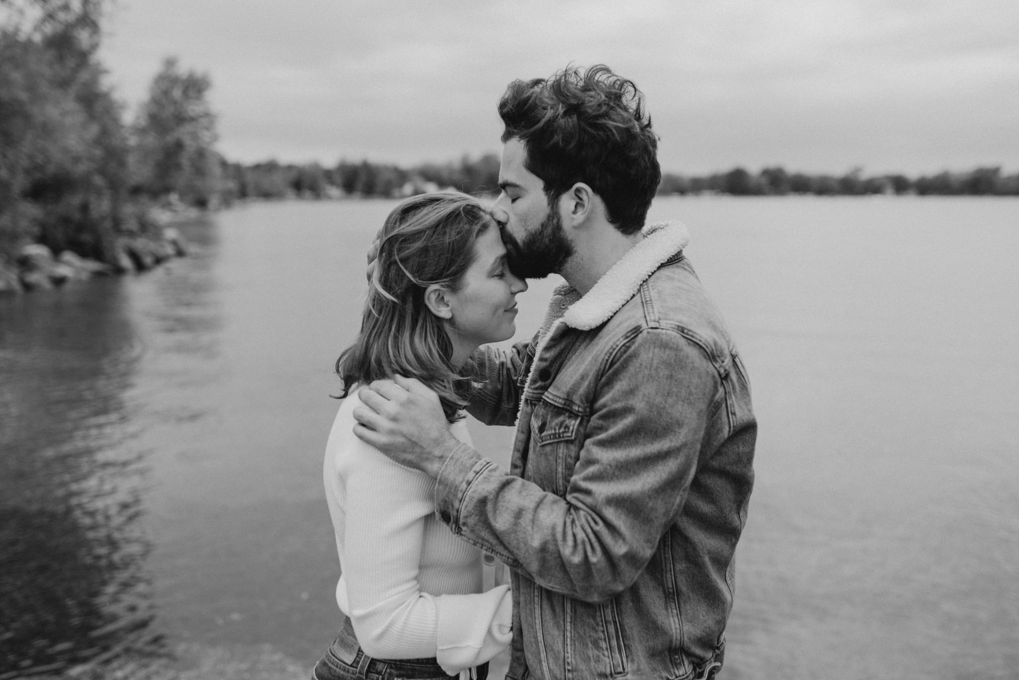 black and white portrait of guy kissing woman's forehead