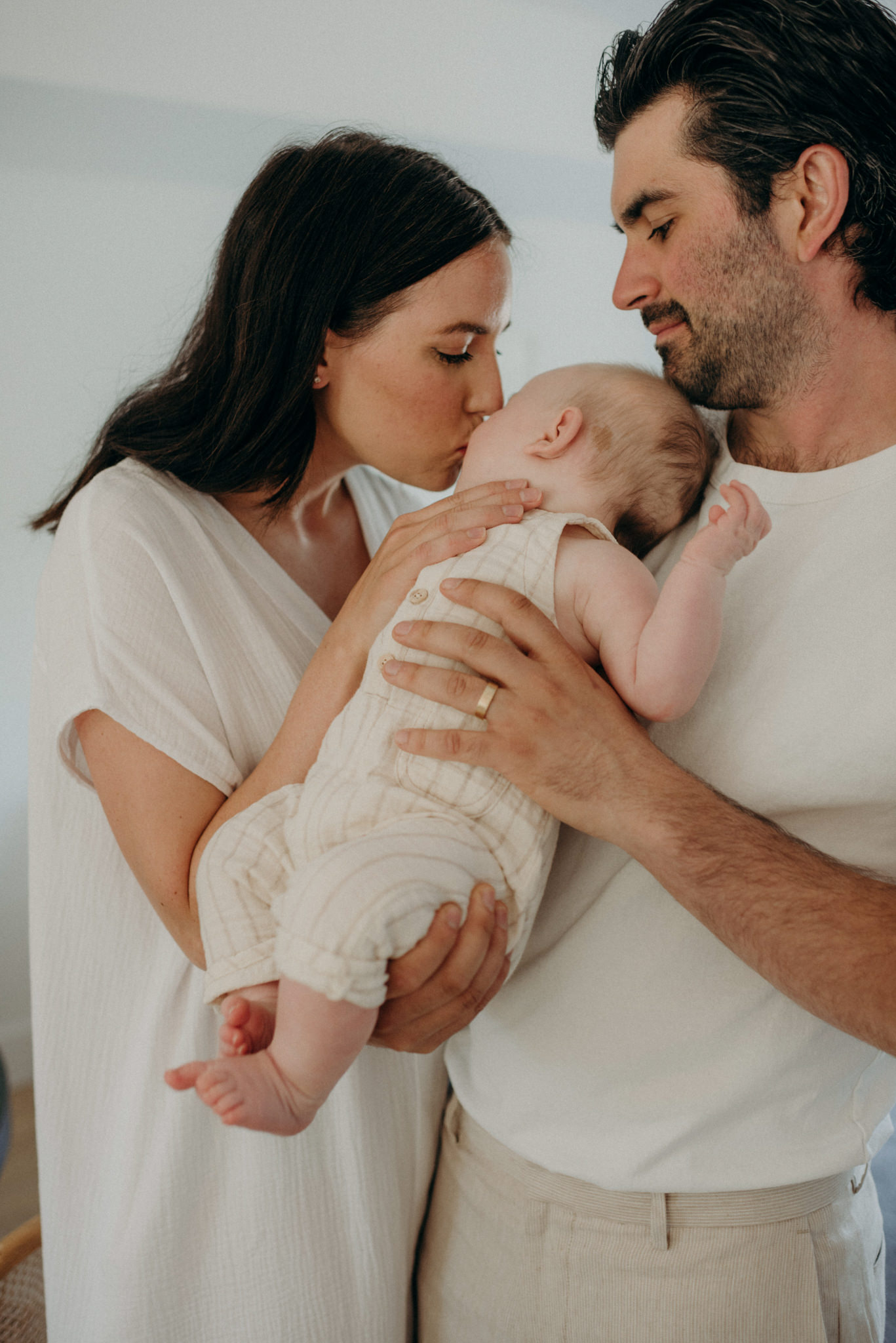 mother kissing baby while father holds