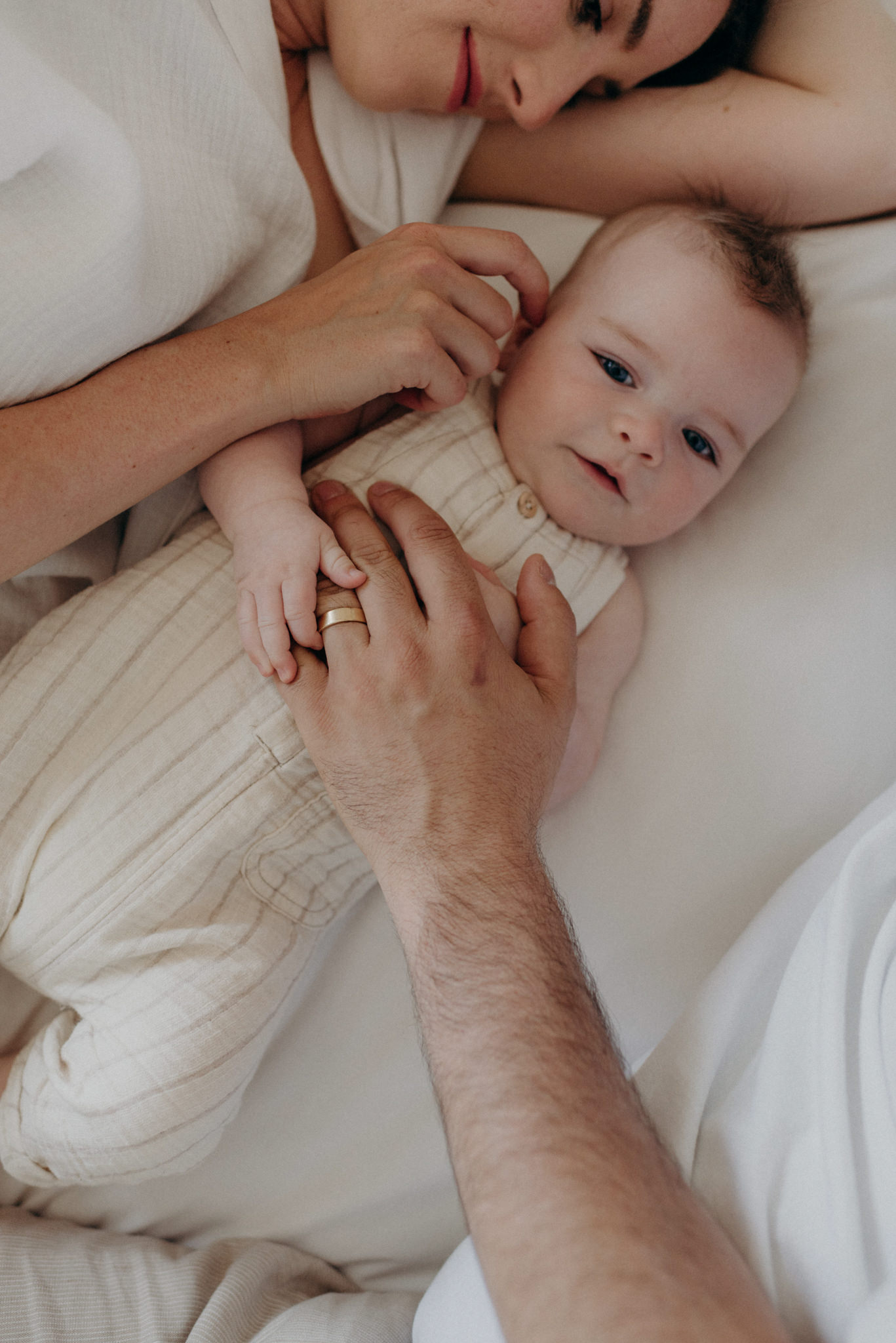 mother and father lying in bed with infant son