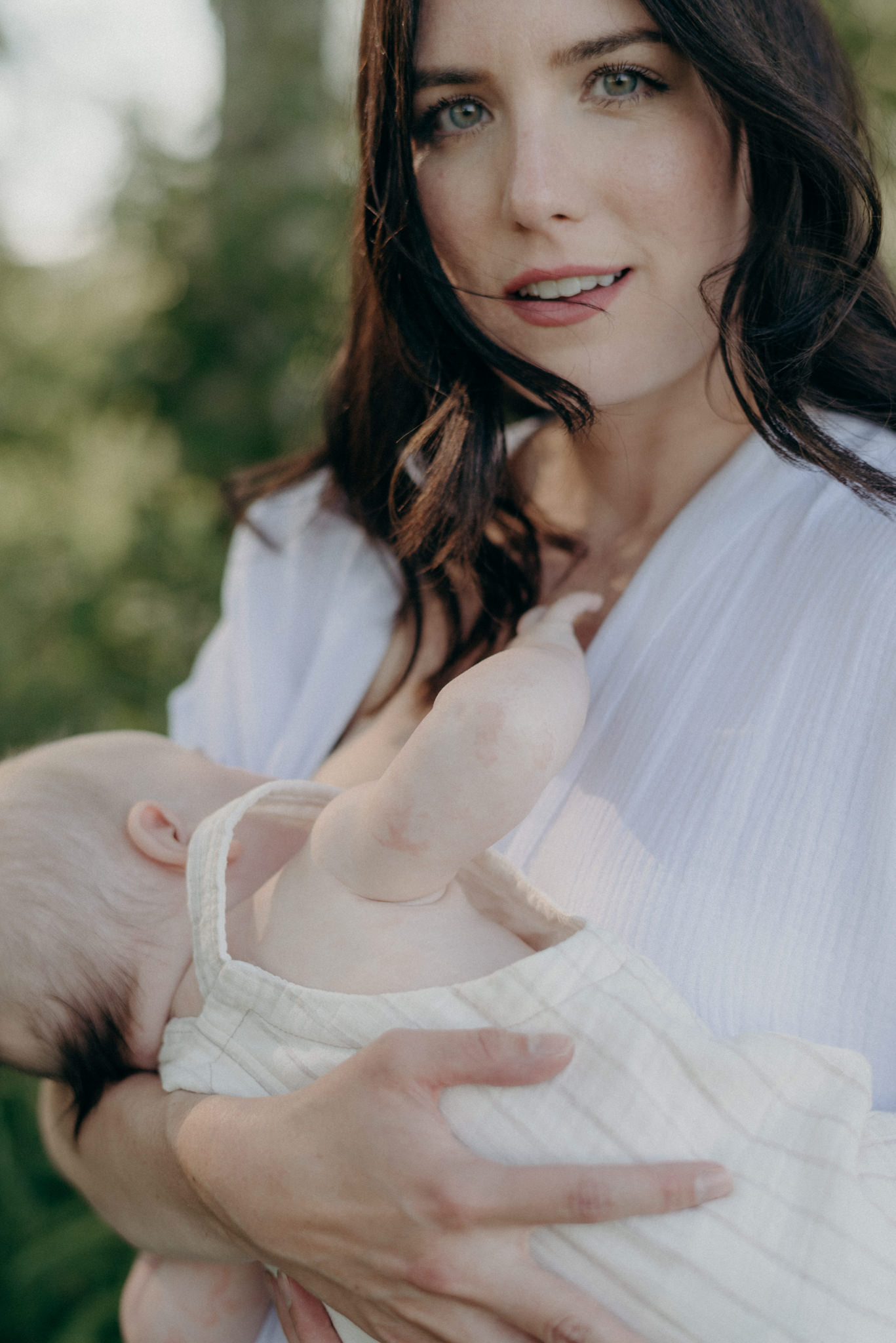 mother breastfeeding baby and looking at camera