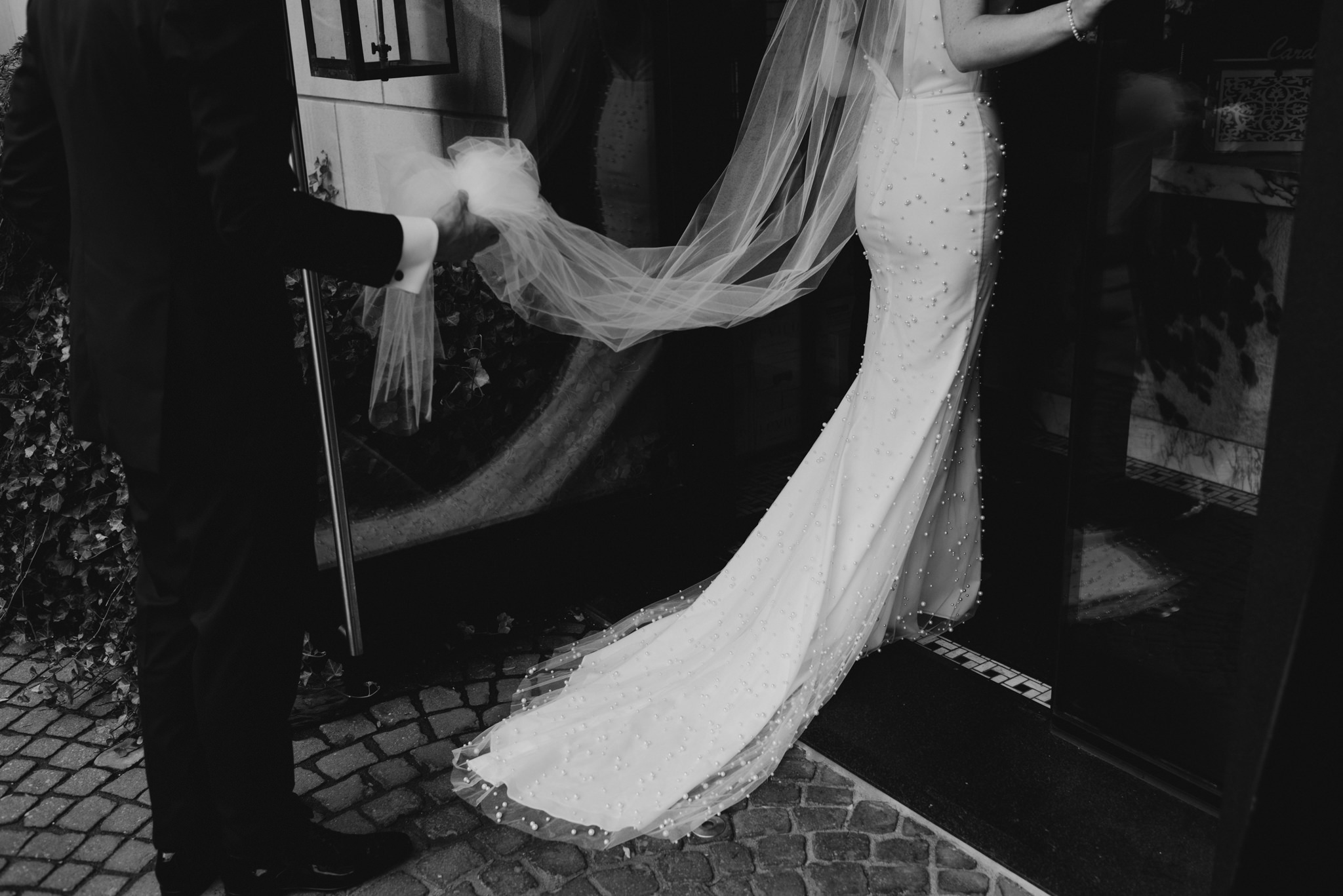 groom holding veil walking into restaurant