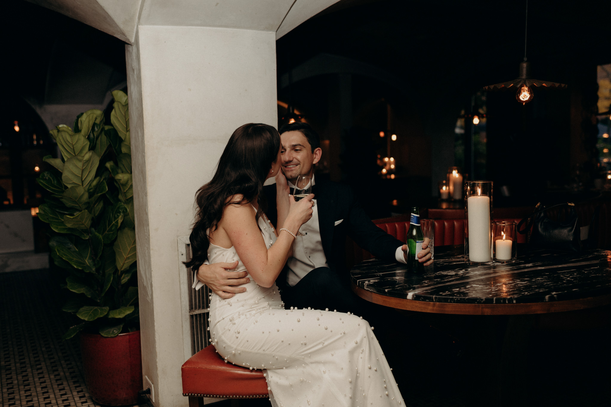 bride and groom kissing in booth at restaurant