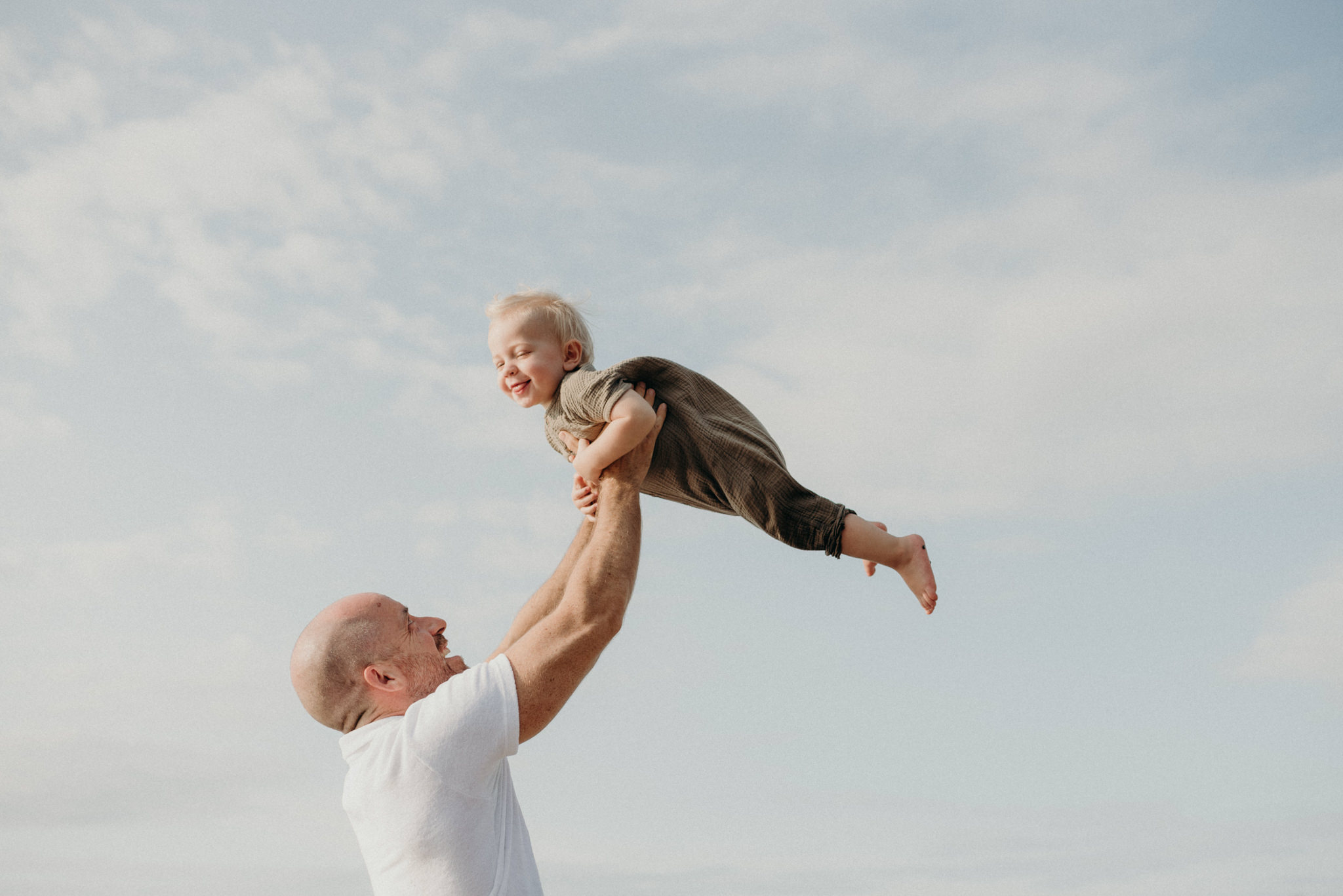 dad throwing toddler son up in the air